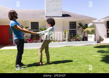 Felice diverse coppie che danzano di fronte a casa sul sole terrazza giardino Foto Stock