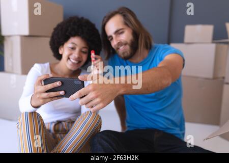 Felice diverse coppie che si muovono casa seduta e utilizzando smartphone Foto Stock