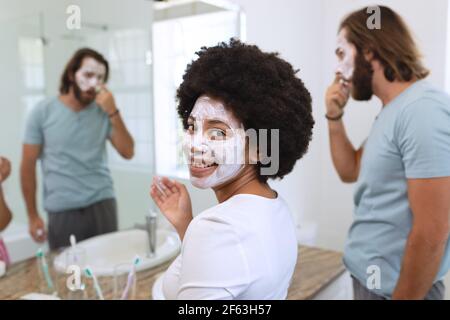 Ritratto di felice coppia diversa in piedi in bagno di bellezza maschere Foto Stock
