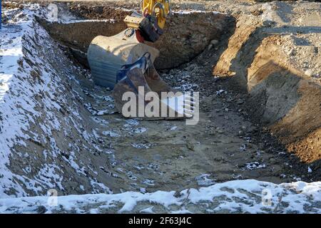 Benna con penetratore bulldozer in una fossa o in un albero di costruzione in un cantiere in inverno con una certa neve. Foto Stock