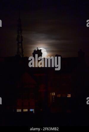Brighton UK 29 marzo 2021 - la Luna di Worm sorge questa sera sopra le case nella zona del Queens Park di Brighton. Questa sarà la prima superluna dell'anno, il che significa che la luna è leggermente più vicina alla Terra e quindi appare più grande e luminosa nel cielo. : Credit Simon Dack / Alamy Live News Foto Stock
