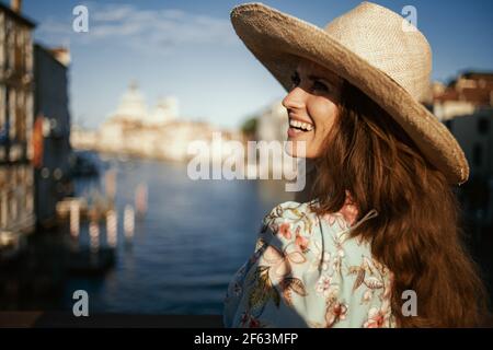 Felice giovane viaggiatore donna in abito floreale con cappello sul ponte dell'Accademia a Venezia, Italia. Foto Stock
