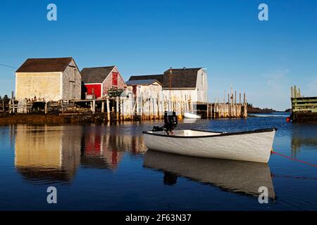 Barca a remi ormeggiata a Blue Rocks in Nuova Scozia, Canada. I capannoni per immagazzinare l'attrezzatura da pesca riflettono nell'acqua. Foto Stock