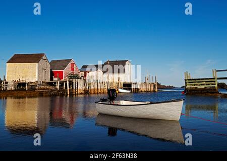 Barca a remi ormeggiata a Blue Rocks in Nuova Scozia, Canada. I capannoni per immagazzinare l'attrezzatura da pesca riflettono nell'acqua. Foto Stock