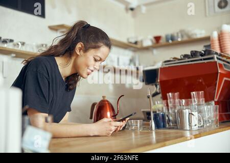 Barista che effettua l'ordine dal cliente online sullo smartphone. Concetto di caffetteria e caffetteria per piccole imprese Foto Stock