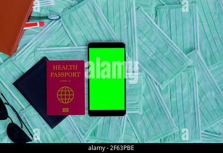 Passaporto e smartphone con schermo verde. Concetto di viaggio con spazio di copia. Salute Passport virus corona vaccino, chroma key mockup Foto Stock