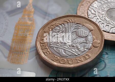 Moneta inglese da una libbra posta sulla banconota da 5 libbre di polimero con il simbolo visibile del Big ben. Concetto. Messa a fuoco selettiva. Macro. Foto Stock