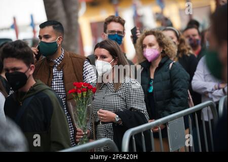 Una donna che indossa una maschera facciale è vista tenere un bouquet di garofani mentre attende per visitare il Cautivo Cristo fuori della fratellanza, come parte del culto della settimana Santa. Nonostante la cancellazione delle processioni per la settimana Santa, molte fraternità hanno deciso di organizzare le messe, Adorazioni e figure di Cristo e della Vergine all'interno di chiese o fraternite che assicurano tutte le misure protettive contro Covid19 sono seguite. Foto Stock