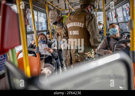 I militari verificano i permessi sanitari dei passeggeri su un autobus di trasporto pubblico.cordicelle sanitarie e controlli di polizia durante il primo giorno di quarantena totale nella zona centrale del paese, dopo il brusco aumento dei casi di Covid-19 nella regione metropolitana, le autorità sanitarie del paese hanno decretato una quarantena totale per la zona centrale del paese. Sebbene il Cile sia leader nel numero di persone vaccinate, l'aumento dei casi positivi mette nuovamente a rischio la stabilità del sistema sanitario. Foto Stock