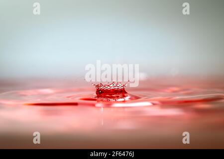 Momento di gocce d'acqua che si scontrano su sfondo rosa. Astratto sfondo naturale Foto Stock