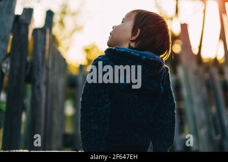 la bambina si siede su una slitta di legno con la schiena e guarda il cielo Foto Stock