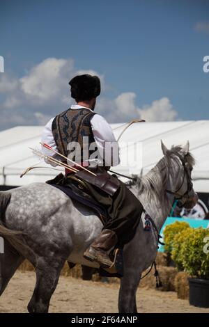 Equitazione con archer in abiti etnici a cavallo Foto Stock