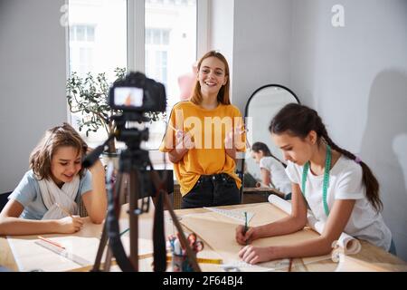 Gioiosa bambina che registra video in laboratorio di cucito Foto Stock