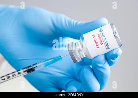Primo piano immagine concettuale che mostra il vaccino COVID 19 progettato per uso pediatrico solo in un flaconcino di vetro con ago e siringa riempita prima che lo shot sia de Foto Stock