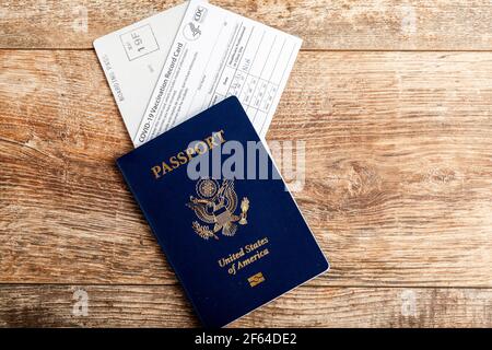 Clarksburg, MD, USA 03-30-2021: Immagine dall'alto piatta di un passaporto statunitense, una carta d'imbarco e una carta di registrazione per la vaccinazione HHS COVID-19 su sfondo di legno Foto Stock