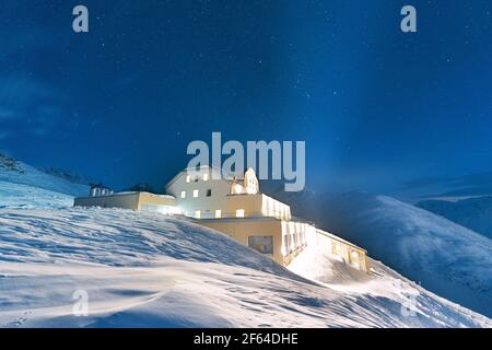 Cielo stellato notturno sulla stazione funicolare in cima alle montagne innevate, Muottas Muragl, Grubunden Canton, Engadina, Svizzera Foto Stock