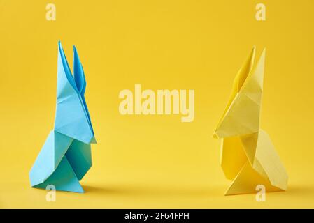 Due conigli colorati di carta origami Esater su sfondo giallo. Concetto di celebrazione pasquale Foto Stock