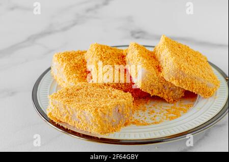 pezzetti di pesce impanati su un piatto preparato per cucinare. Foto Stock