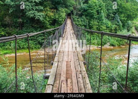 Ponte di sospensione, attraversando il fiume, ferriage nei boschi Foto Stock