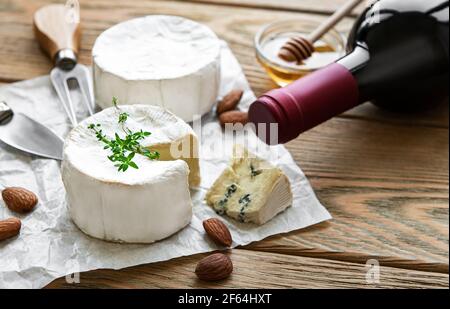 Vari tipi di formaggio, formaggio blu, bree, camambert e vino su un tavolo di legno Foto Stock