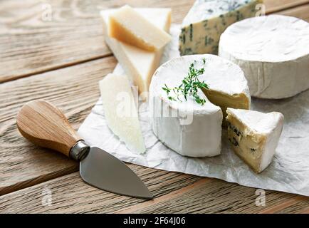 Vari tipi di formaggio, formaggio blu, bree, camambert su un tavolo di legno Foto Stock