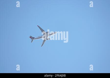 Aereo che vola nel cielo azzurro, vista dal basso e laterale. Aereo commerciale decollo e guadagnare quota Foto Stock