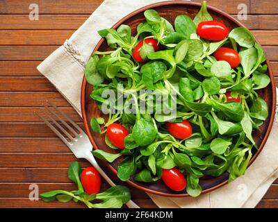 Ciotola in legno con insalata di mais, lattuga di agnello e pomodori ciliegini Foto Stock