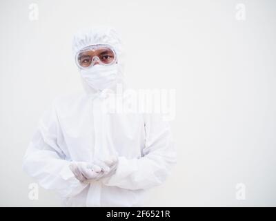 Ritratto di giovane medico o scienziato asiatico in uniforme DPI suite tenendo le mani mentre si guarda avanti. Coronavirus o COVID-19 concetto isolato bianco Foto Stock