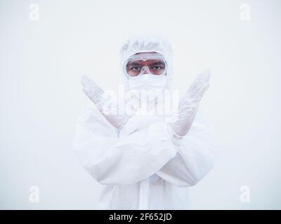 Medico o scienziato asiatico in suite PPE uniforme mostrando x segno con le braccia per smettere di fare qualcosa mentre si guarda avanti. Gesturing stop, avvertimento di d Foto Stock