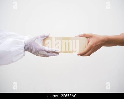 Concetto di coronavirus o COVID-19. Contatto protetto tra corriere e cliente durante la quarantena su sfondo bianco Foto Stock