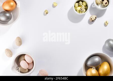 Molte uova di Pasqua multicolore in ciotole di diverse misure su uno sfondo bianco Foto Stock