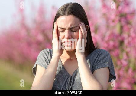 Donna che soffre di emicrania in un campo fiorito in un sole giorno Foto Stock