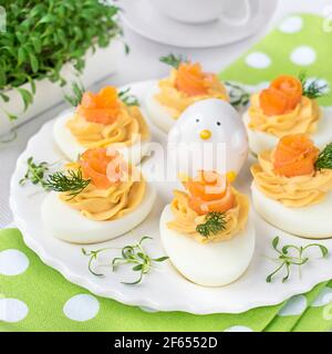 Uova farcite con pasta di salmone affumicata, decorate con pezzi di salmone e aneto fresco. Foto Stock