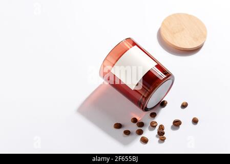 Candele di soia in bottiglie di vetro ambrato scuro con mockup coperchio e chicchi di caffè su sfondo bianco. Primo piano, confezione di marca minima Foto Stock