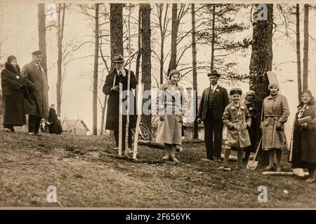 Lettonia - CIRCA 1930: Persone che piantano alberi. Foto di gruppo nella foresta. Vintage archivio Art deco era foto Foto Stock
