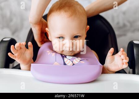 Un bambino sorridente in un seggiolino in attesa di cibo Foto Stock