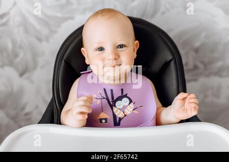 Un bambino sorridente in un seggiolino in attesa di cibo Foto Stock