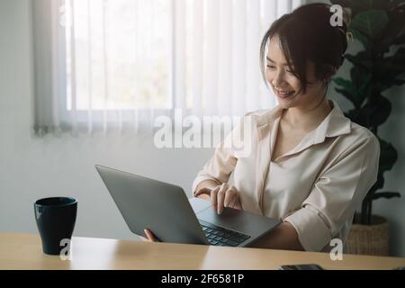 Donna d'affari sorridente che lavora su un computer portatile a casa - Online riunione della conferenza Foto Stock