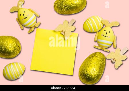 Uova di Pasqua, decorazioni e note appiccicose gialle su sfondo rosa. Foto Stock