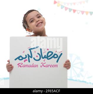 Happy Girl Holding Ramadan Greeting Board, Arabo testo traduzione 'Santo Beato mese di Ramadan' Foto Stock