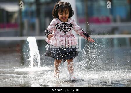 Birmingham, Regno Unito. 30 Marzo 2021. Hallah, di due anni, suona nella fontana di Centenary Square nel centro di Birmingham. Credit: Peter Lopeman/Alamy Live News Foto Stock