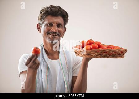 un agricoltore indiano che tiene un cestino di pomodoro con pomodoro Foto Stock
