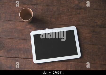 Moderno spazio di lavoro per ufficio con tablet pc sul tavolo e una tazza di caffè usa e getta. Per una presentazione o un portfolio di progetti. Foto Stock