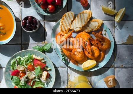 Piatti mediterranei a tavola: Gamberi di mare, insalata di verdure, zuppa di zucca, semi Foto Stock