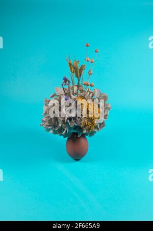 Composizione moderna minimalista astratta, uovo di Pasqua con fiori secchi e motivi floreali diversi. Uovo che rappresenta un vaso. Fiori che crescono fuori Foto Stock