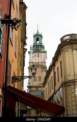 Una strada stretta a Gamla Stan, Stoccolma, Svezia, con edifici colorati su entrambi i lati e la torre di Storkyrkan visibile oltre. Foto Stock