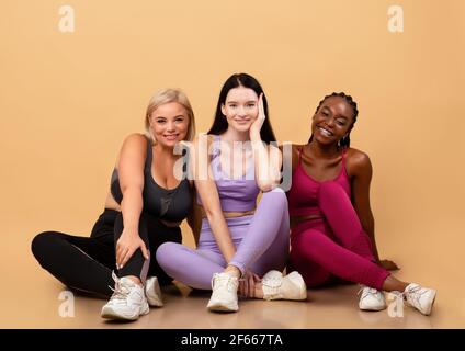 Portraif di tre diverse sorridenti Multi etniche Signore in posa Abbigliamento sportivo Foto Stock