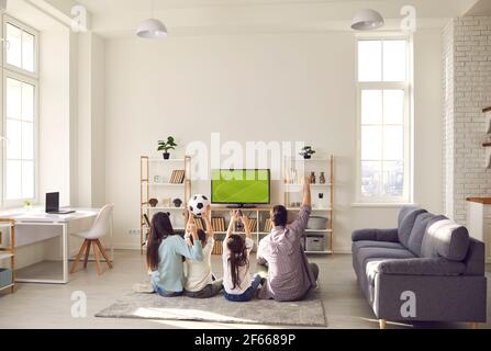 Felice famiglia eccitato con i bambini che guardano partita di calcio in tv a casa Foto Stock