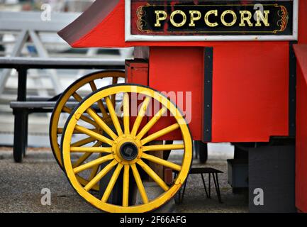 Carretto di popcorn in legno rosso d'epoca con ruote gialle luminose sul molo del porto di Santa Cruz in California, Stati Uniti. Foto Stock