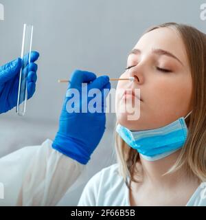 Diagnostica test pazienti coronavirus covid. Medico che prende PCR test coltura nasofaringea a paziente di donna. Infermiere prelevare il campione di saliva attraverso il naso Foto Stock